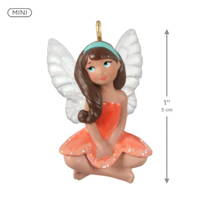 Miniature fairy figurine with white wings and an orange dress, featuring a measurement indicator on a white background.