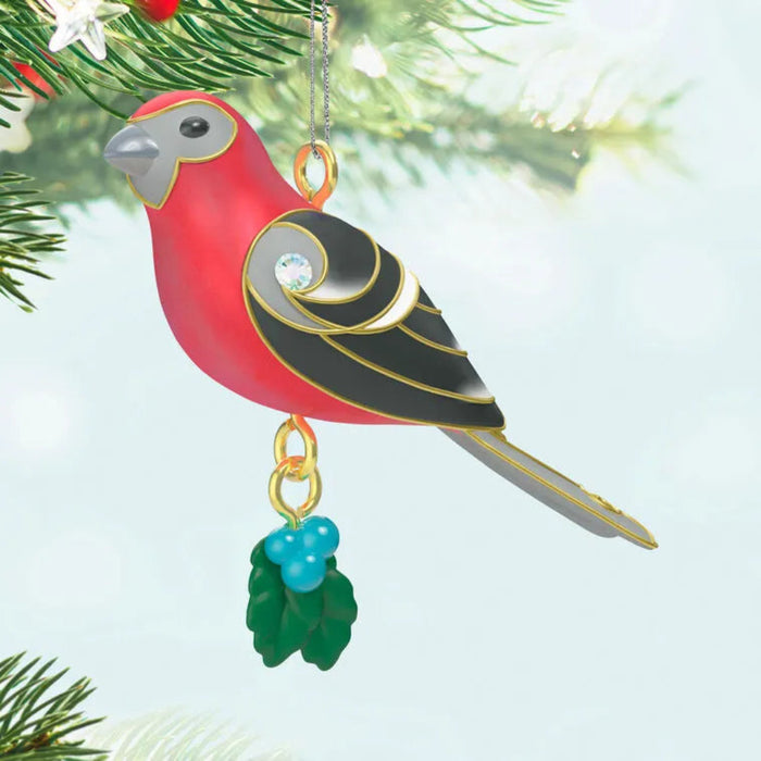 Decorative bird ornament with red, black, and gold colors hanging on a Christmas tree.