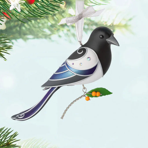 Decorative bird ornament hanging on a branch with a white ribbon.