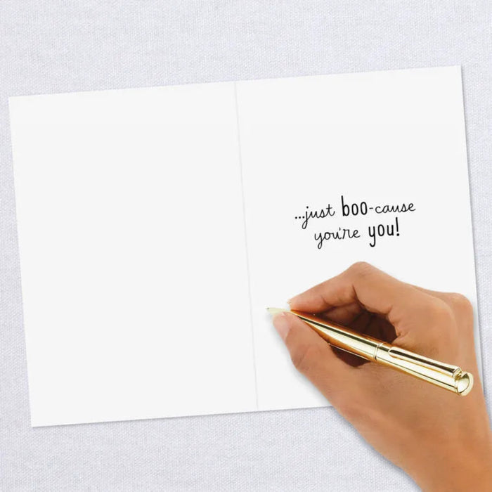 Hand holding a gold pen over a white card with text on a light gray background