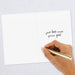 Hand holding a gold pen over a white card with text on a light gray background