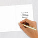 Hand holding a gold pen over a white card with a New Year's message.