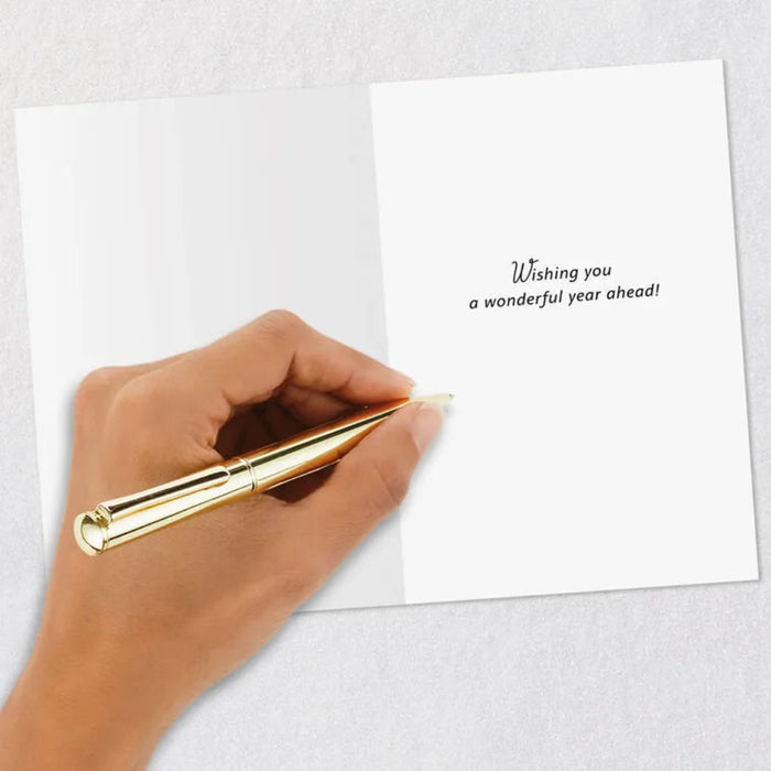 Hand holding a gold pen over a white card with a message on a light gray background