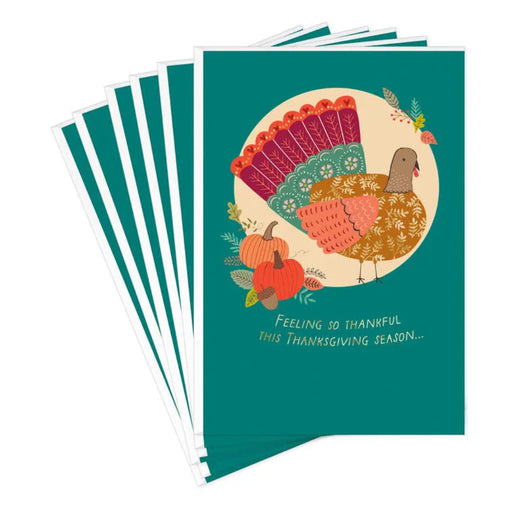 Stack of greeting cards with a turkey illustration and text on a teal background