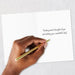 Hand writing on a card with a gold pen, text 'Thinking warm thoughts of you and wishing you a wonderful day.'