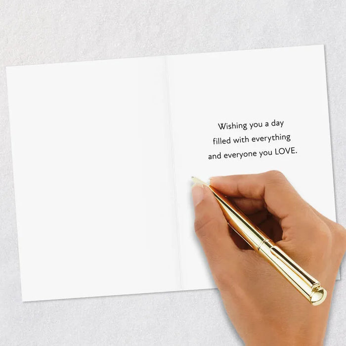 Hand holding a gold pen over a white card with a message on a light gray background