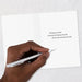 Hand writing on a card with a pen, set against a white background