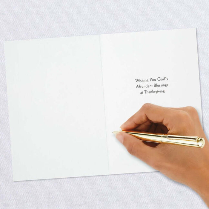 Hand writing on a Religious  Thanksgiving card with a gold pen.
