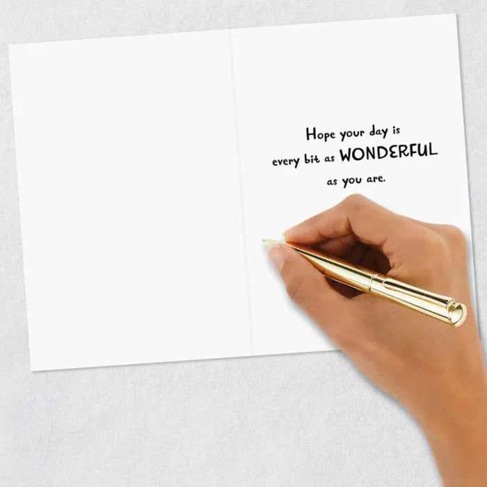 Hand holding a gold pen above a card with a motivational message on a light gray background