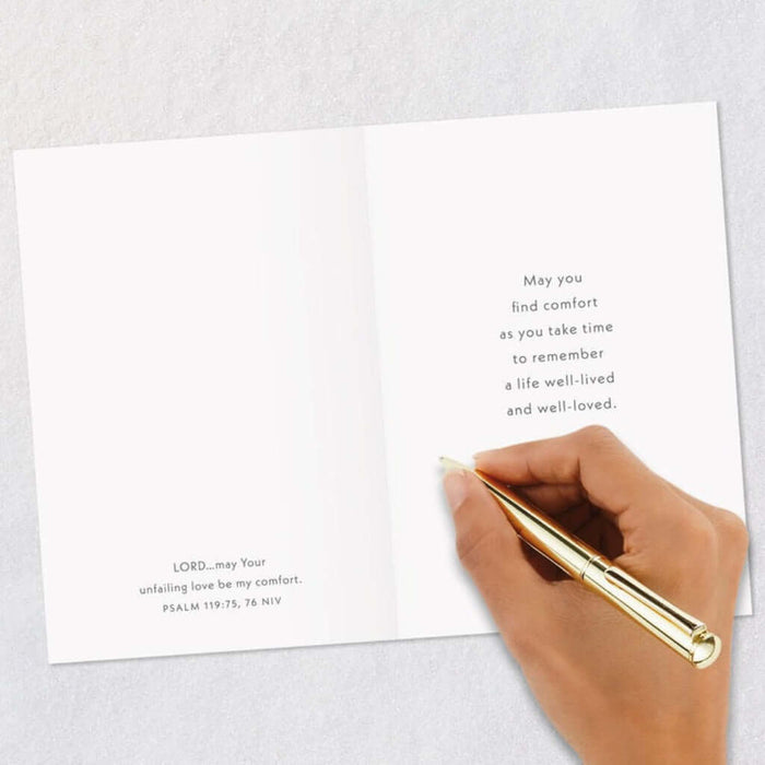 Hand holding a gold pen over a white card with text on a light gray background