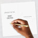 Hand holding a gold pen over a Christmas card with text