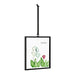 A hanging picture frame displays a vibrant cactus alongside a colorful flower against a neutral background.