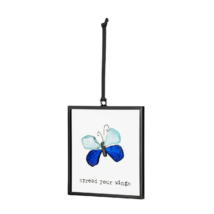 A blue butterfly with outstretched wings sits on a leaf, emphasizing its beautiful blue tones and delicate structure.