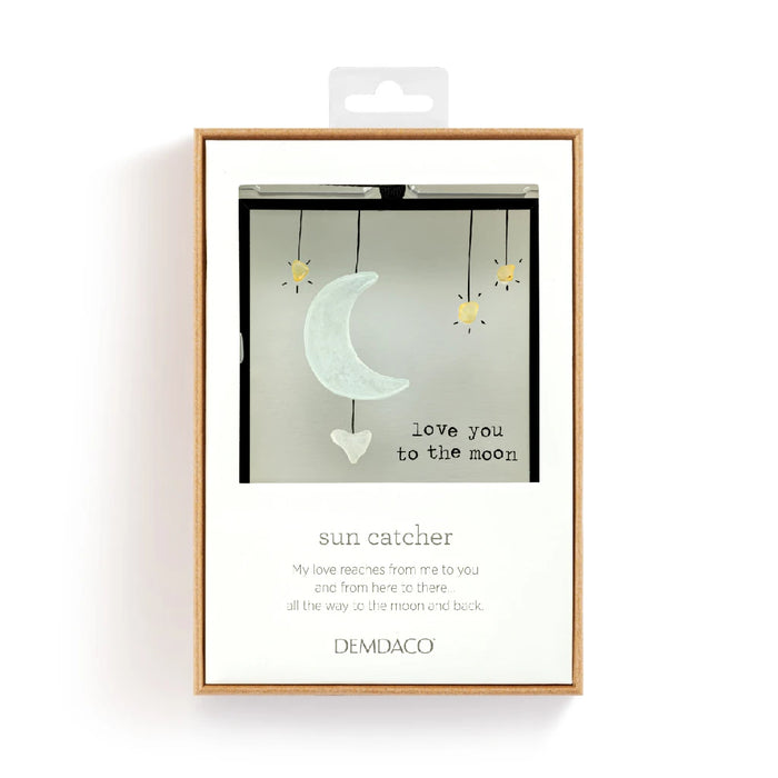 A decorative ornament featuring a crescent moon and an inspirational quote hanging against a soft background.