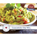 A bowl of creamy guacamole dip mix, garnished with cilantro and served with tortilla chips on the side.