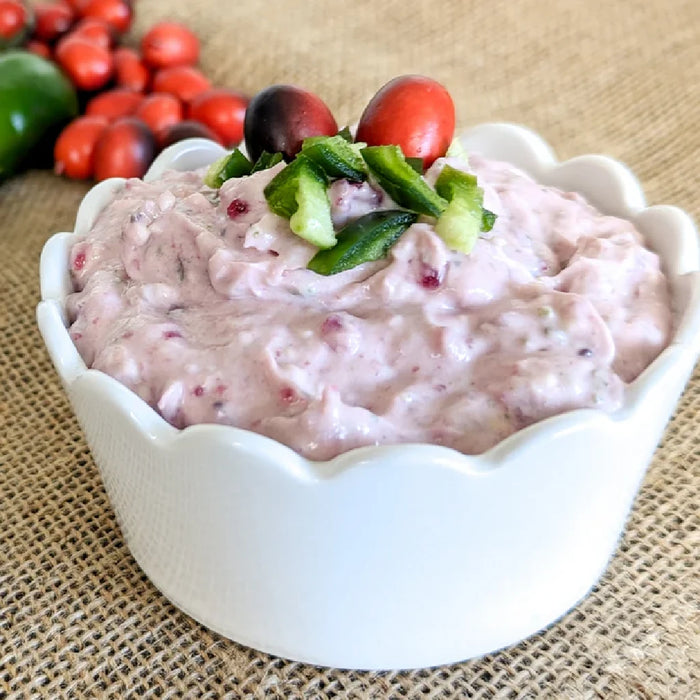 A vibrant cranberry jalapeño spread mix in a jar, featuring a rich red color and visible jalapeño pieces for flavor.