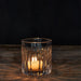 Two candles are placed in a clear glass holder, creating a serene ambiance with their gentle flickering light.