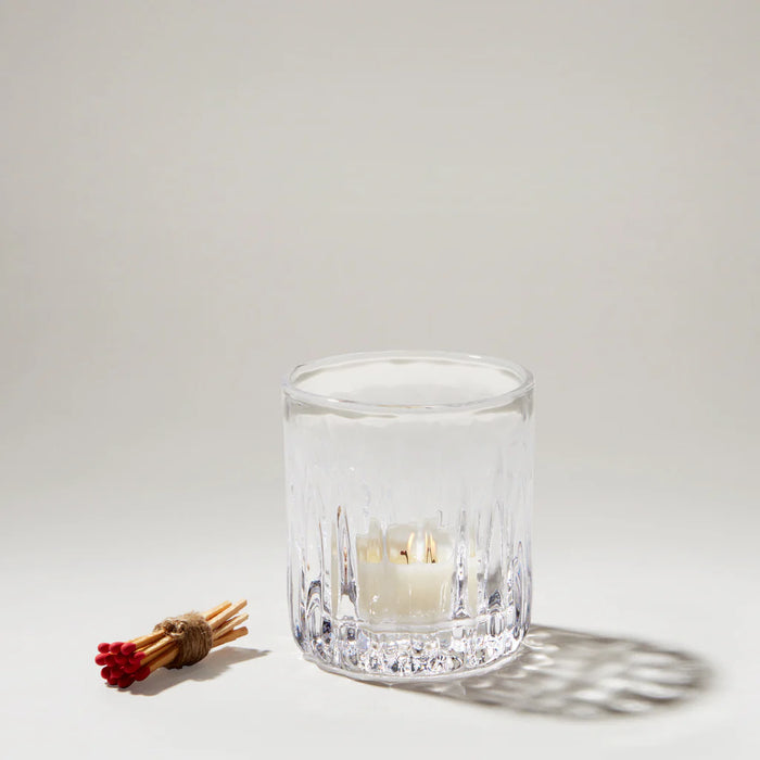 A clear glass candle holder features two candles, enhancing the decor with their soft illumination and elegant design.