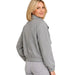 A woman wearing a light gray heathered fleece jacket with a high collar and elastic cuffs, shown from a three-quarters back view against a plain white background.