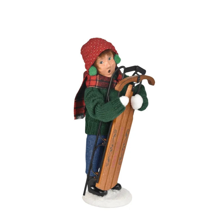 Decorative figurine of a boy child holding a sled on a white background