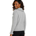 A woman wearing a light gray knit sweater with a ruffled collar and ruffled cuffs, shown from a side-back angle against a plain white background.