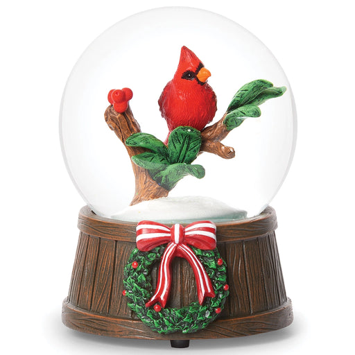 Snow globe with a red cardinal bird on a branch and a Christmas wreath on a wooden base.