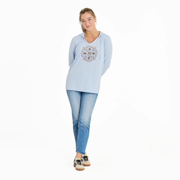 Woman wearing a light blue hoodie with a floral design and jeans on a white background