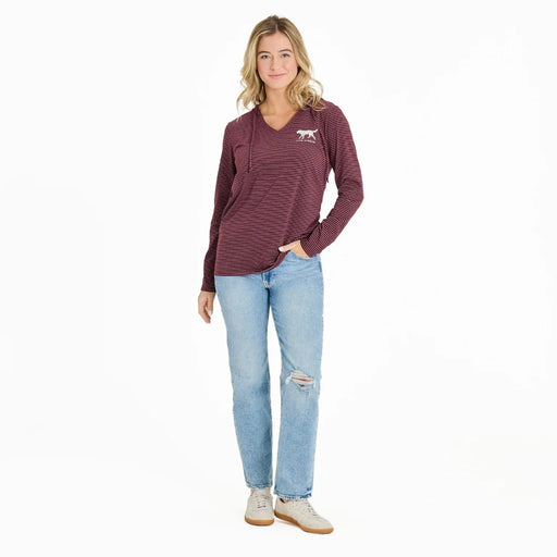 Woman wearing a maroon striped long-sleeve shirt and light blue jeans on a white background