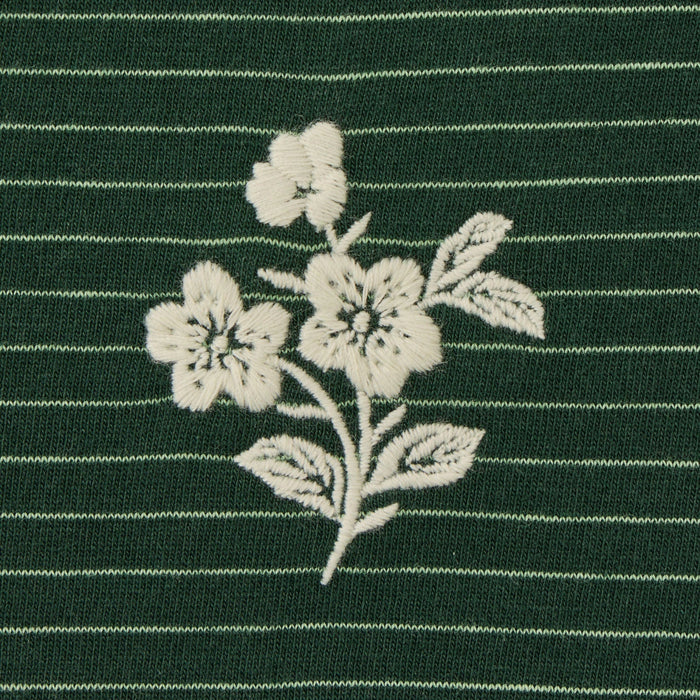 White floral embroidery on a green striped fabric background