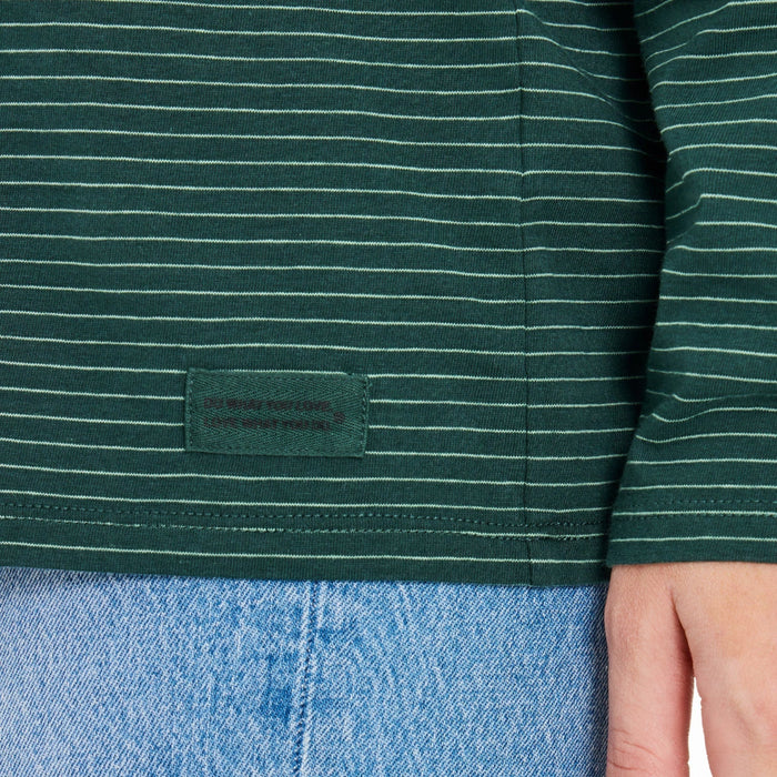 Close-up of a green striped shirt with "Do what you love. Love what you do." label, worn over blue jeans.