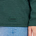 Close-up of a green striped shirt with "Do what you love. Love what you do." label, worn over blue jeans.