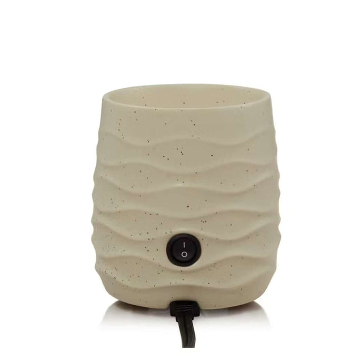 Beige textured electric candle warmer with power button on a white background