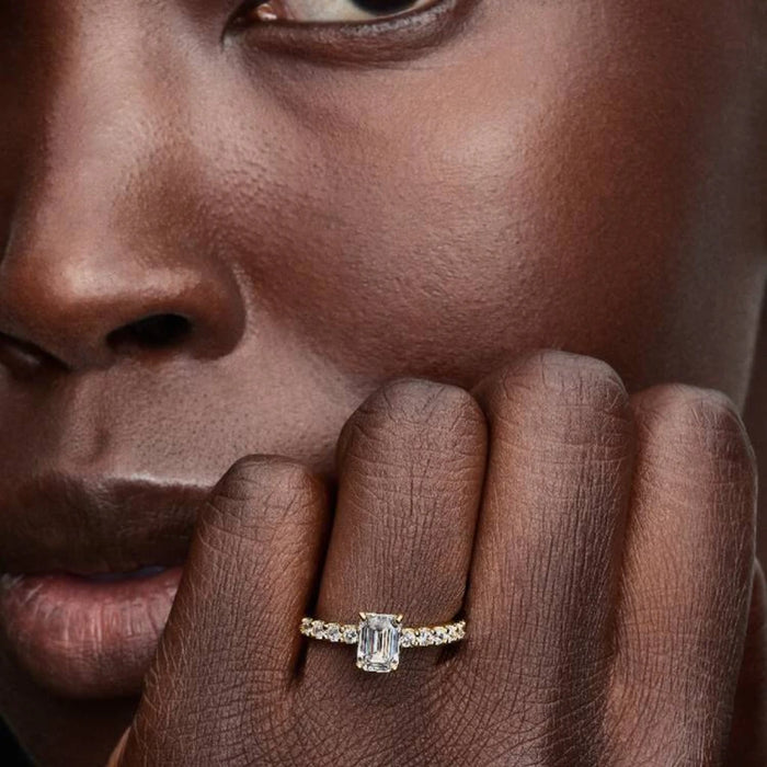 An exquisite yellow gold engagement ring with an emerald cut diamond, perfect for a proposal or special occasion.