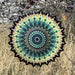 A circular design made of paper, displaying a blend of blue and green hues in a decorative pattern.