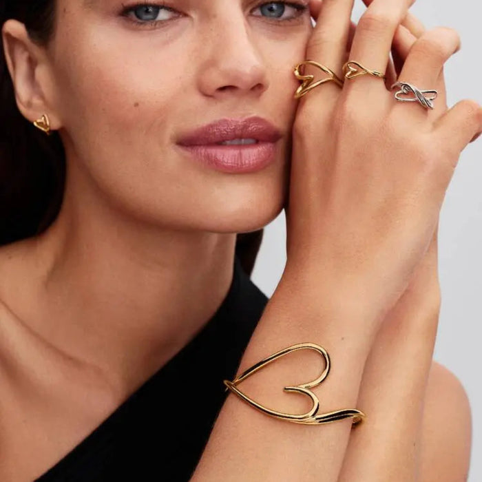 Pandora Organically Shaped Heart Small Ring in sterling silver worn on a woman’s finger with other rings and a bracelet, close-up view.