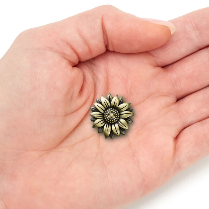 Bronze sunflower pocket token displayed in a person’s hand to show scale