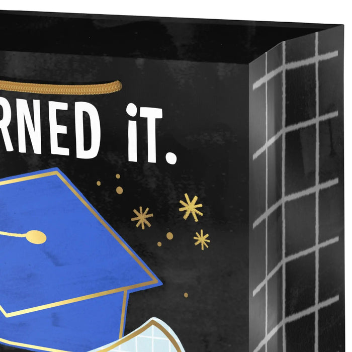 Close‑up of black graduation gift bag with blue cap and gold accents
