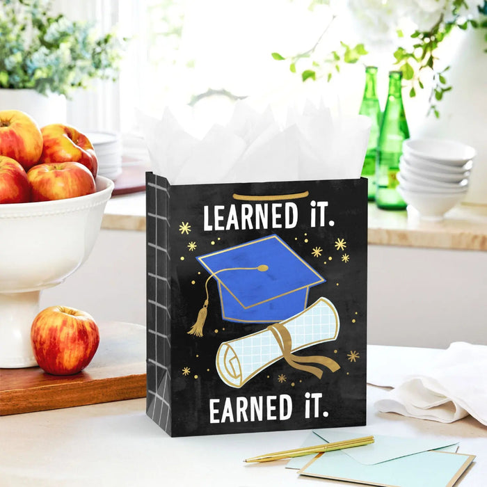 Starry black graduation gift bag with blue cap, diploma, and gold foil details styled on a tabletop with a matching card