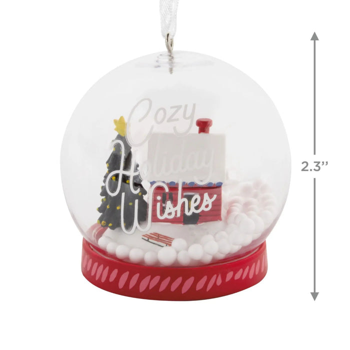 Hallmark Cozy Holiday Wishes Snow Globe Christmas ornament featuring a red log cabin, snowy roof, decorated evergreen tree, and swirling white snowballs.