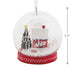 Hallmark Cozy Holiday Wishes Snow Globe Christmas ornament featuring a red log cabin, snowy roof, decorated evergreen tree, and swirling white snowballs.