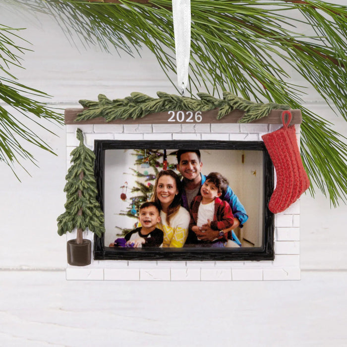 Hallmark Cozy Fireplace 2026 Photo Frame Christmas ornament featuring a festive fireplace with greenery, red stocking, miniature evergreen tree, and photo holder.