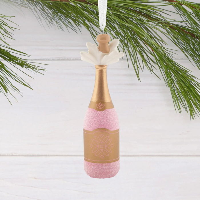 Hallmark Pink Champagne Christmas ornament featuring a gold-wrapped bottle with sparkling pink champagne bubbles bursting from the cork.
