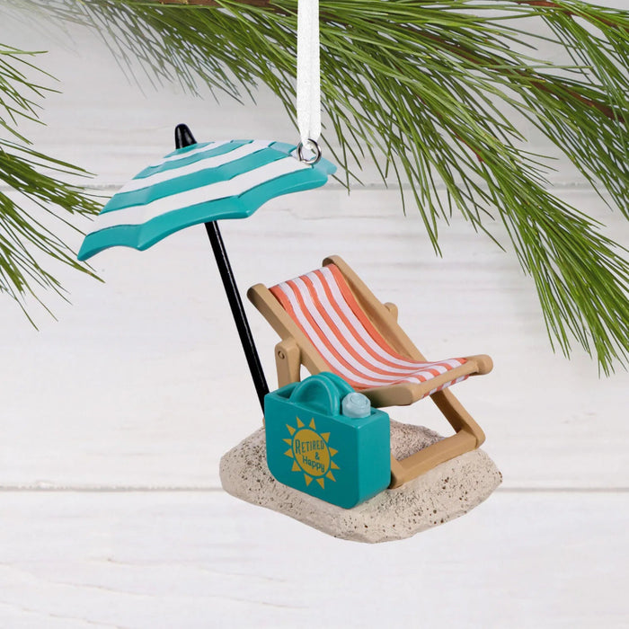 Hallmark Retired and Happy Christmas ornament featuring a beach chair, umbrella, sand, and beach bag with “Retired & Happy” message.