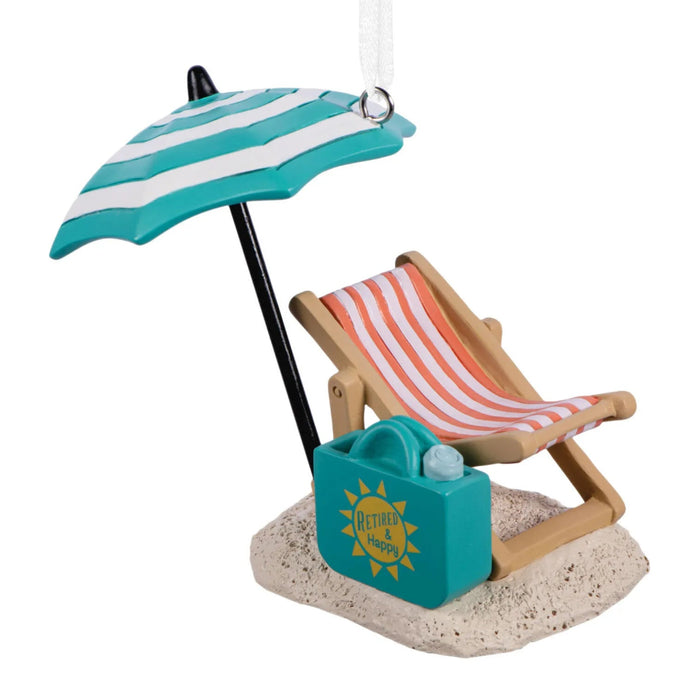 Hallmark Retired and Happy Christmas ornament featuring a beach chair, umbrella, sand, and beach bag with “Retired & Happy” message.