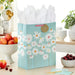 Extra‑large blue daisy Mother’s Day gift bag with gold accents displayed on a table beside a greeting card