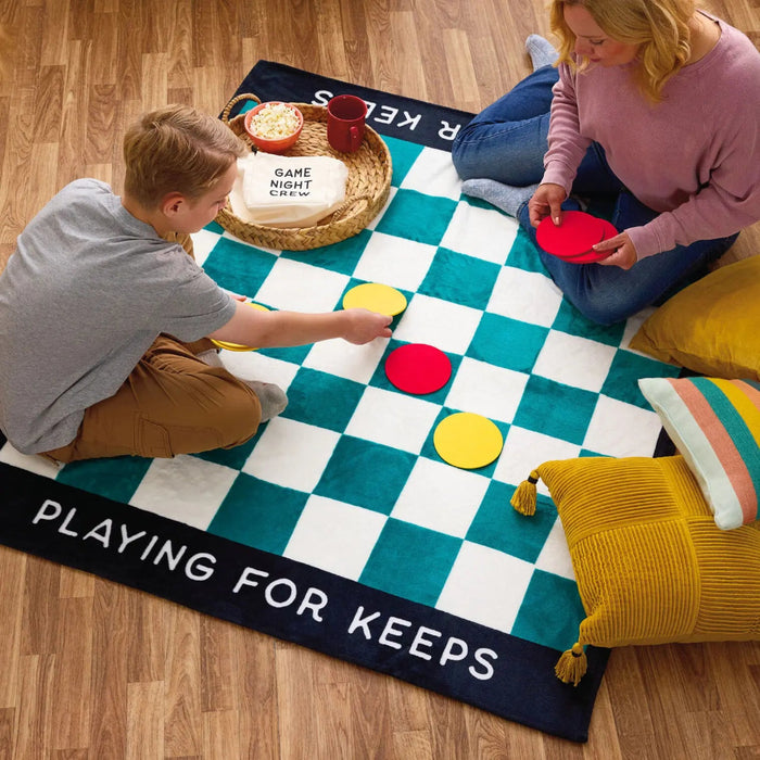 People playing checkers on the teal checkerboard blanket