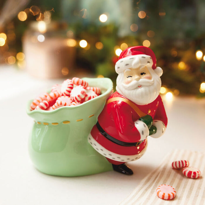 Decorative Santa Claus figure with a bowl of peppermints against a festive background.