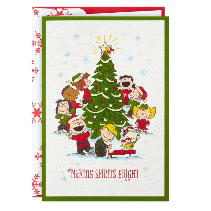 Hallmark Peanuts Gang Christmas cards featuring Snoopy and friends caroling around a decorated Christmas tree, pack of 16.