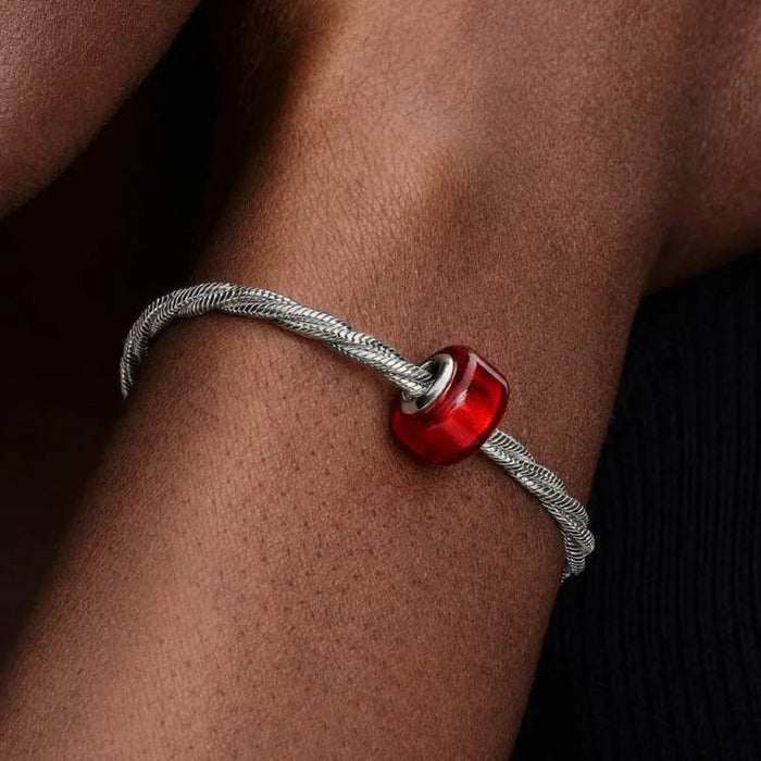 Bracelet with a red bead on a wrist against a dark background
