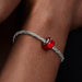 Bracelet with a red bead on a wrist against a dark background